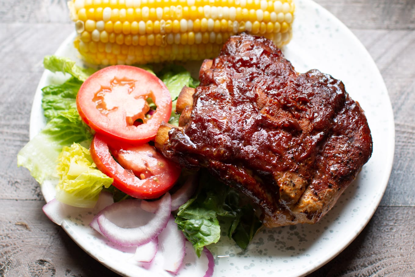 Ribs on a plate with salad and corn