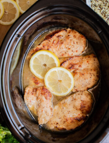 close up of lemon chicken breasts in a slow cooker.