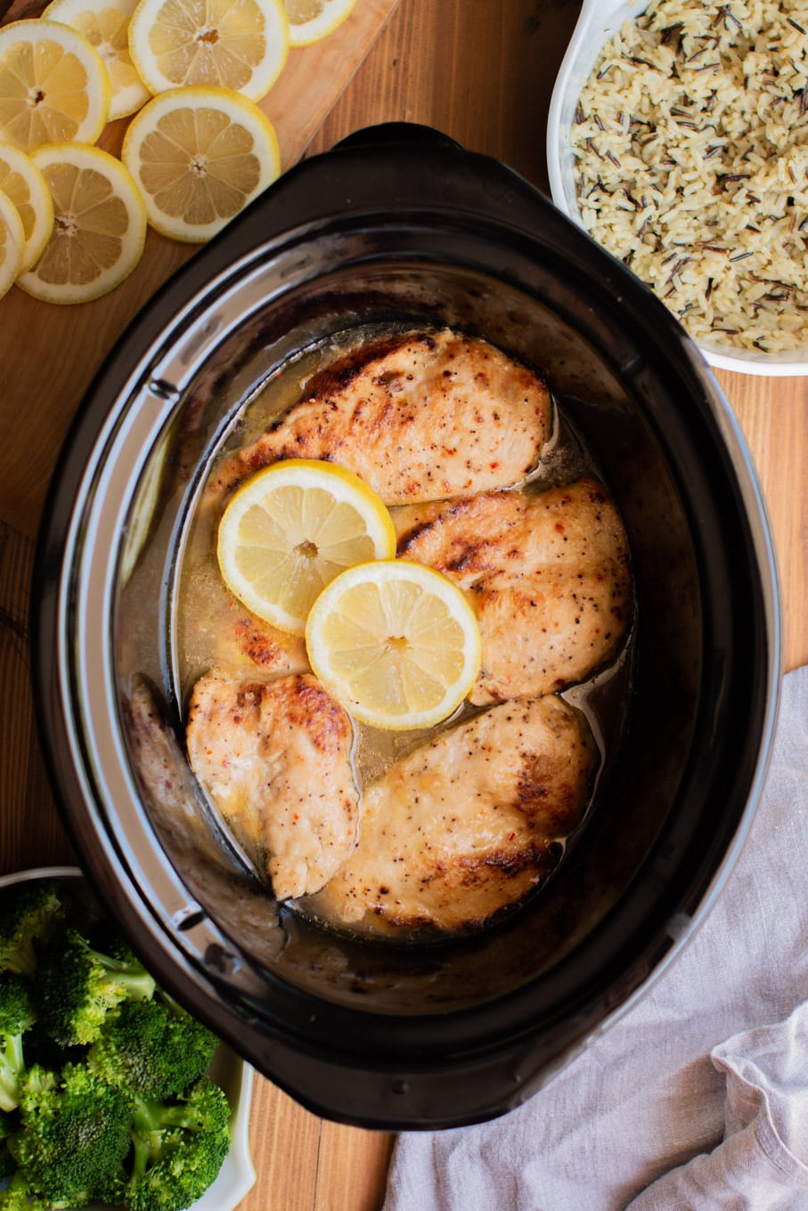 lemon chicken in sauce in a slow cooker with rice pilaf on the side.