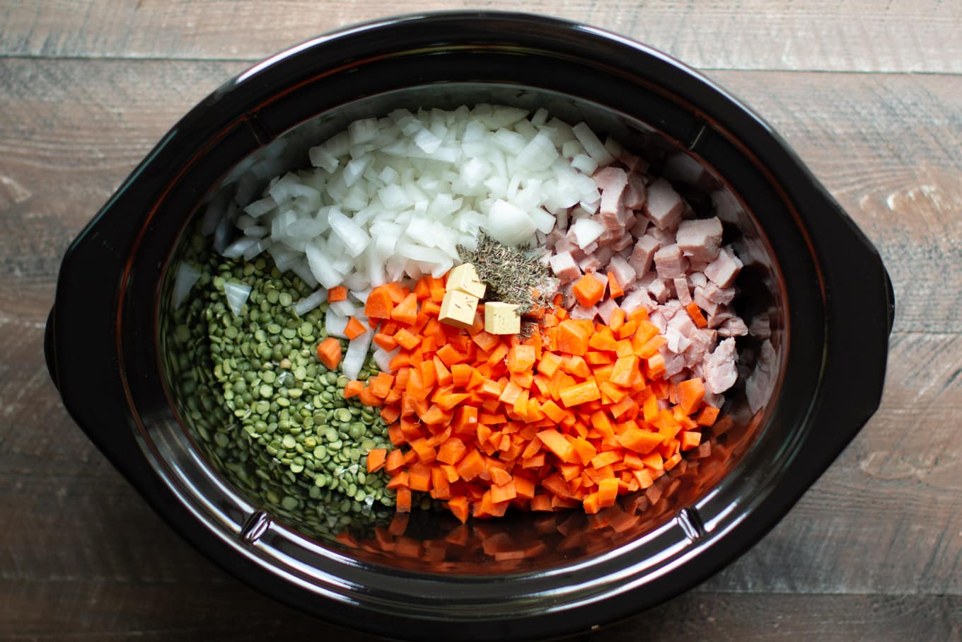 Slow Cooker with diced onion, carrots, ham, split peas, chicken bouillon, and thyme all separated.