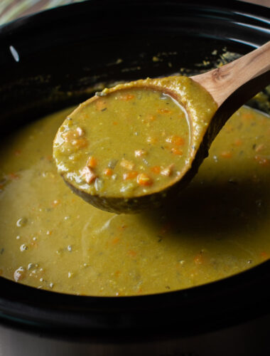 ladle full of split pea soup coming from the slow cooker.