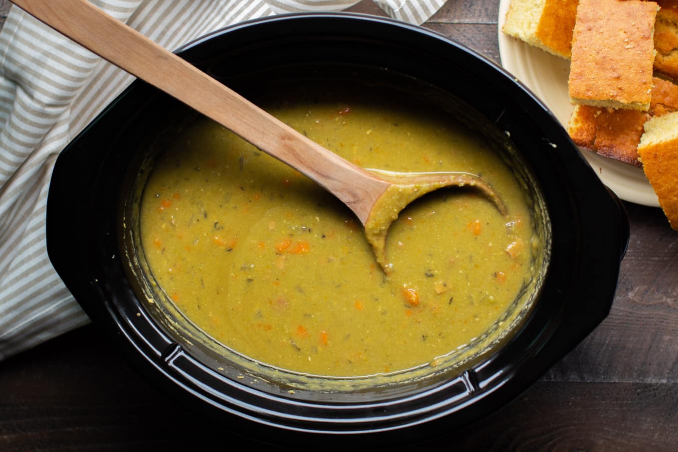 Cooked split pea soup with large wooden ladle in it.