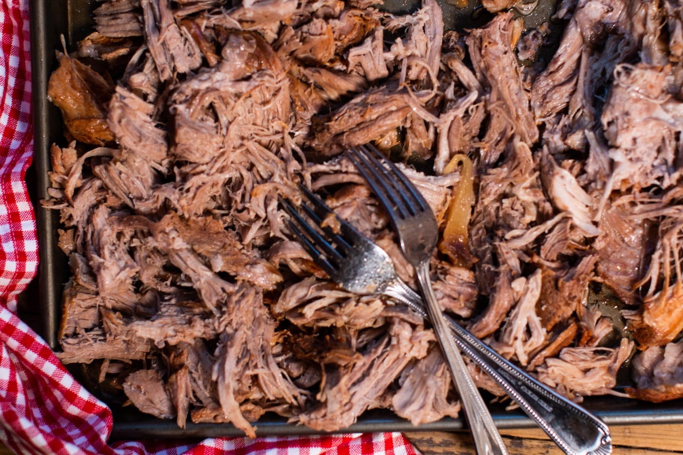 shredded pulled pork on sheet pan with 2 forks on top