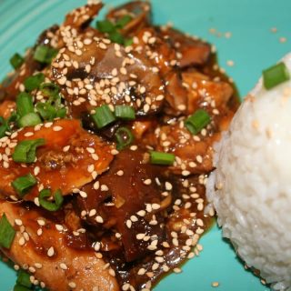 sesame chicken with sesame seeds and green onion on top.
