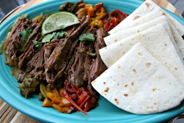 Steak Fajitas with tortillas on teal plate