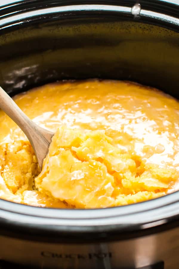 Lemon cake in slow cooker with wooden spoon in it.