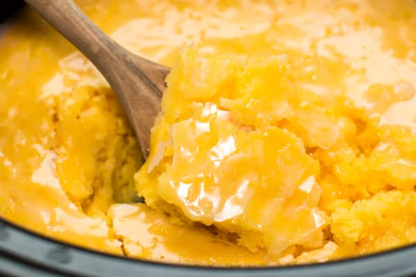 Close up of lemon cake in slow cooker with wooden spoon inside.