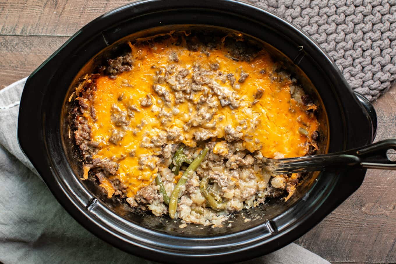 Cooked tater tot casserole in slow cooker, metal spoon inside