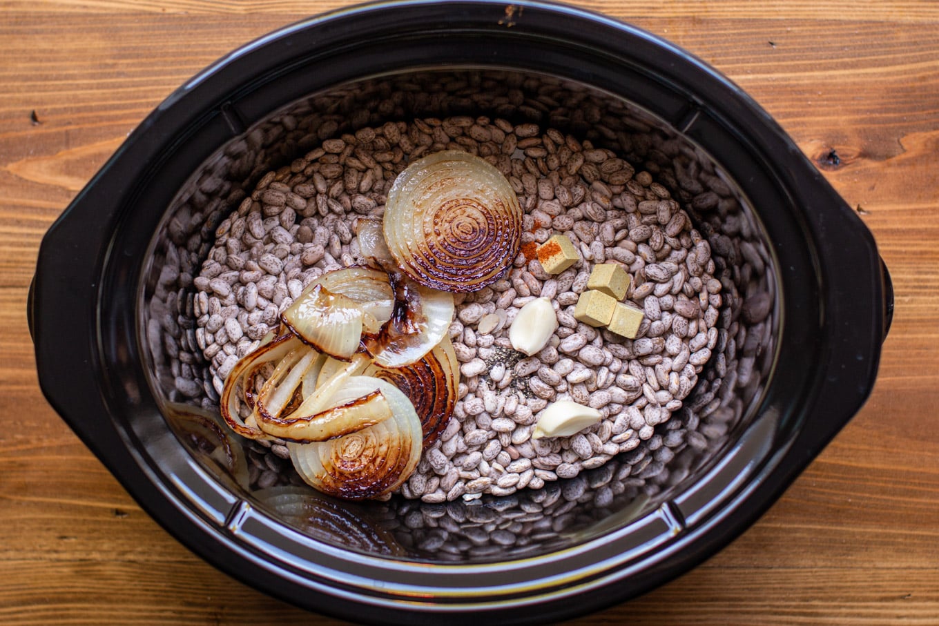 pinto beans in a slow cooker with fried onions, garlic, cayenne pepper and chicken bouillon cubes.