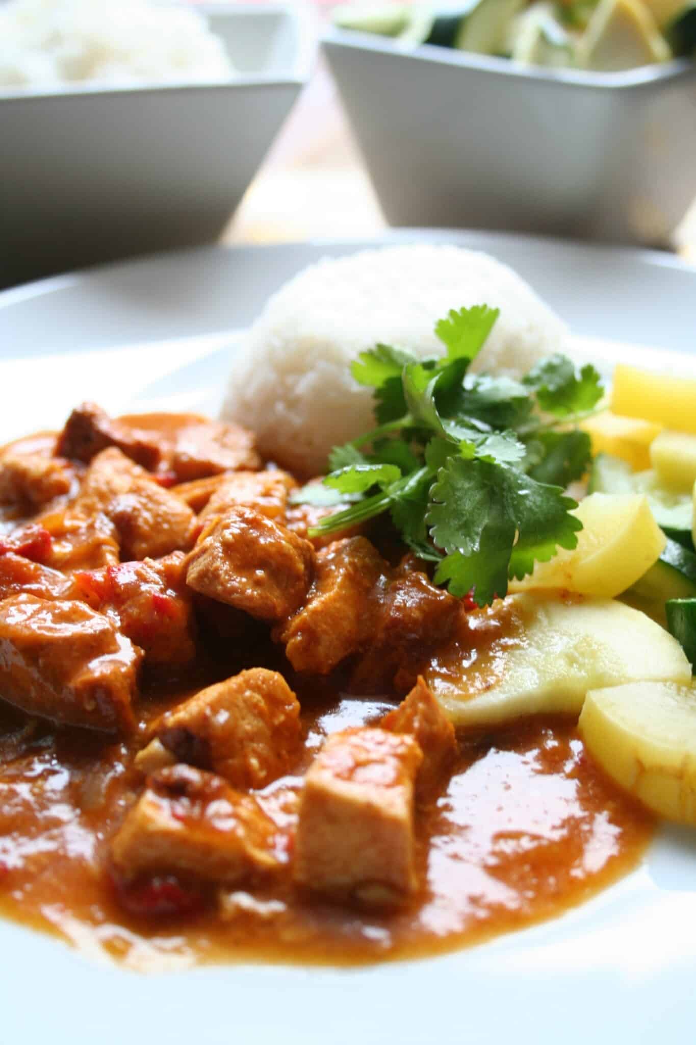 Chicken curry on a plate with rice, zucchini, and cilantro