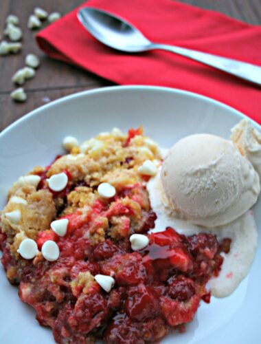 White Chocolate Cherry Dump Cake in white bowl with ice cream on top