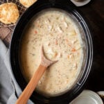 chicken pot pie filling in slow cooker with wooden spoon inside