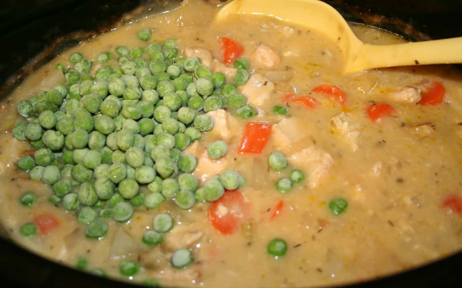 cooked soup with frozen peas on top.