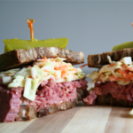 Reuben Sandwich cut in half on cutting board