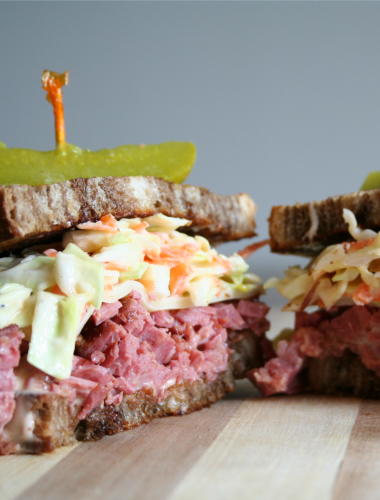 Reuben Sandwich cut in half on cutting board