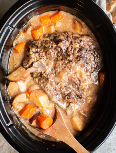 cooked pot roast with cooked vegetables around it.