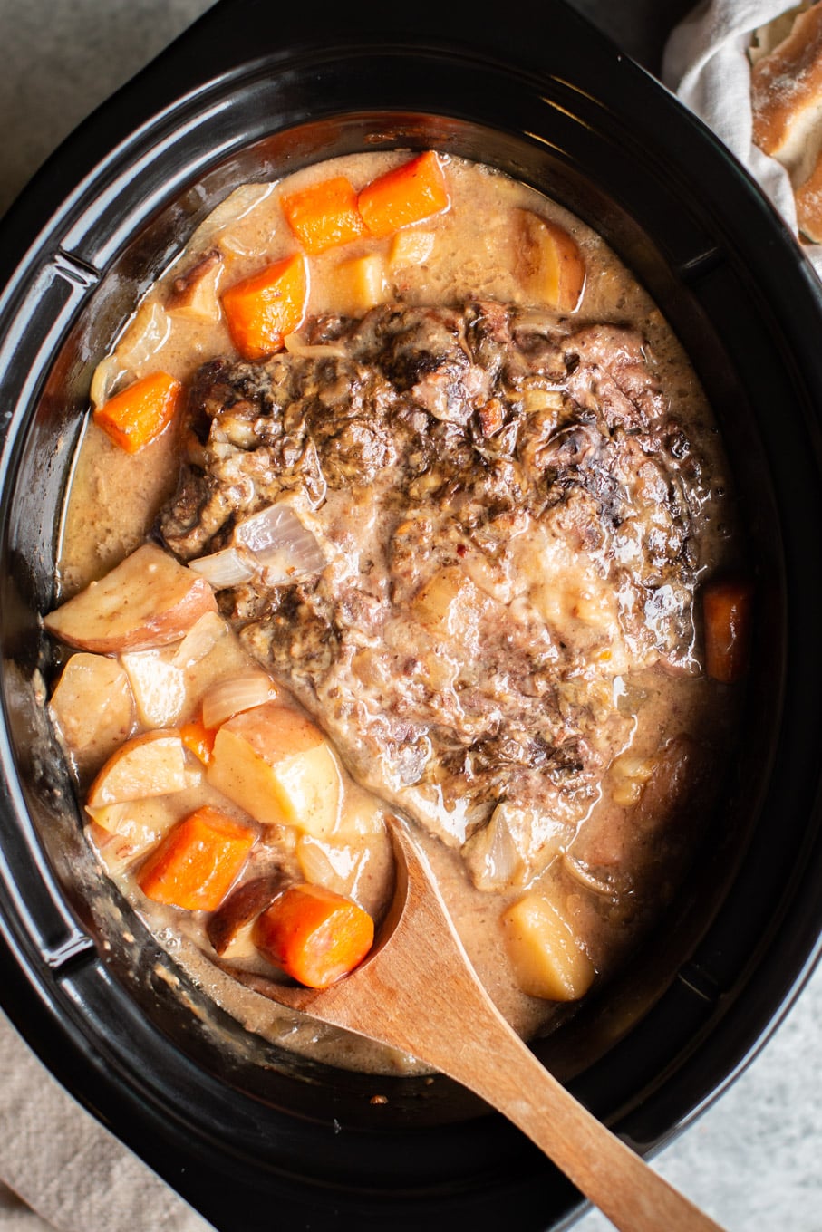 close up of pot roast in gravy in a slow cooker.