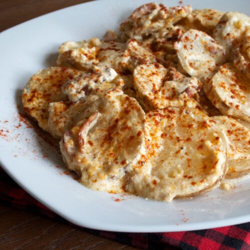 scalloped potatoes with paprika on top on white plate