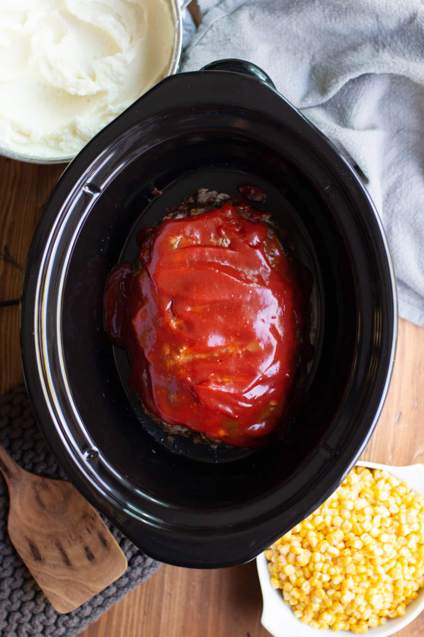 cooked meat loaf in a slow cooker with sauce on top.