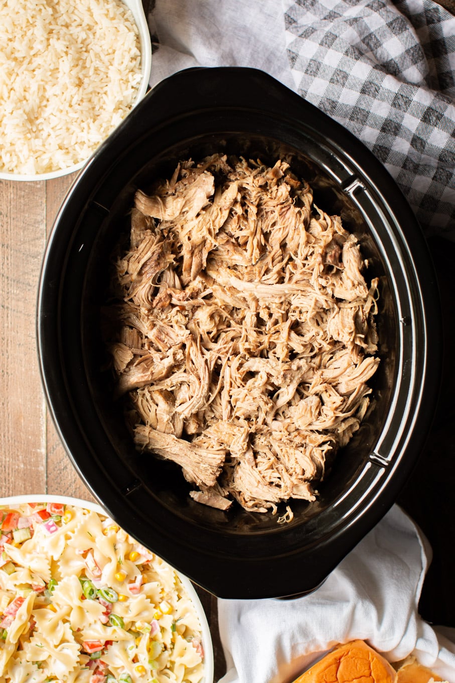 Shredded Hawaiian style pork in a slow cooker with pasta salad and rice on the side.
