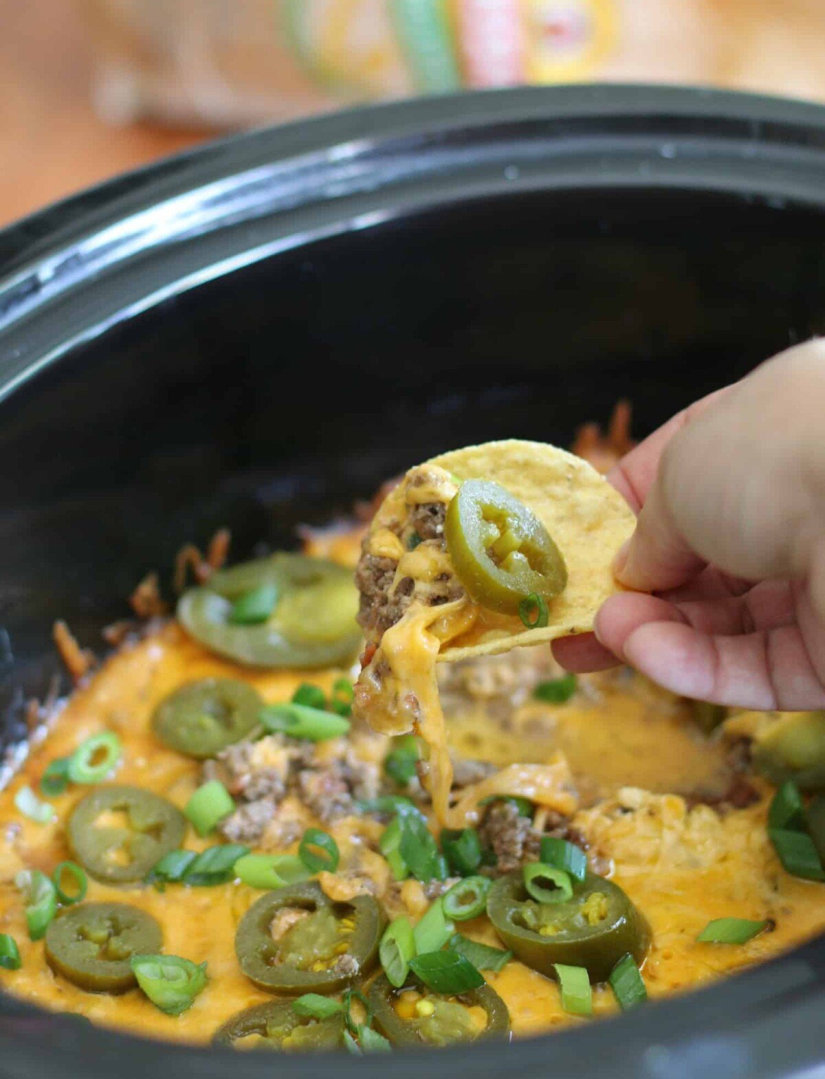 7 layer dip with cheesy chip in a hand.