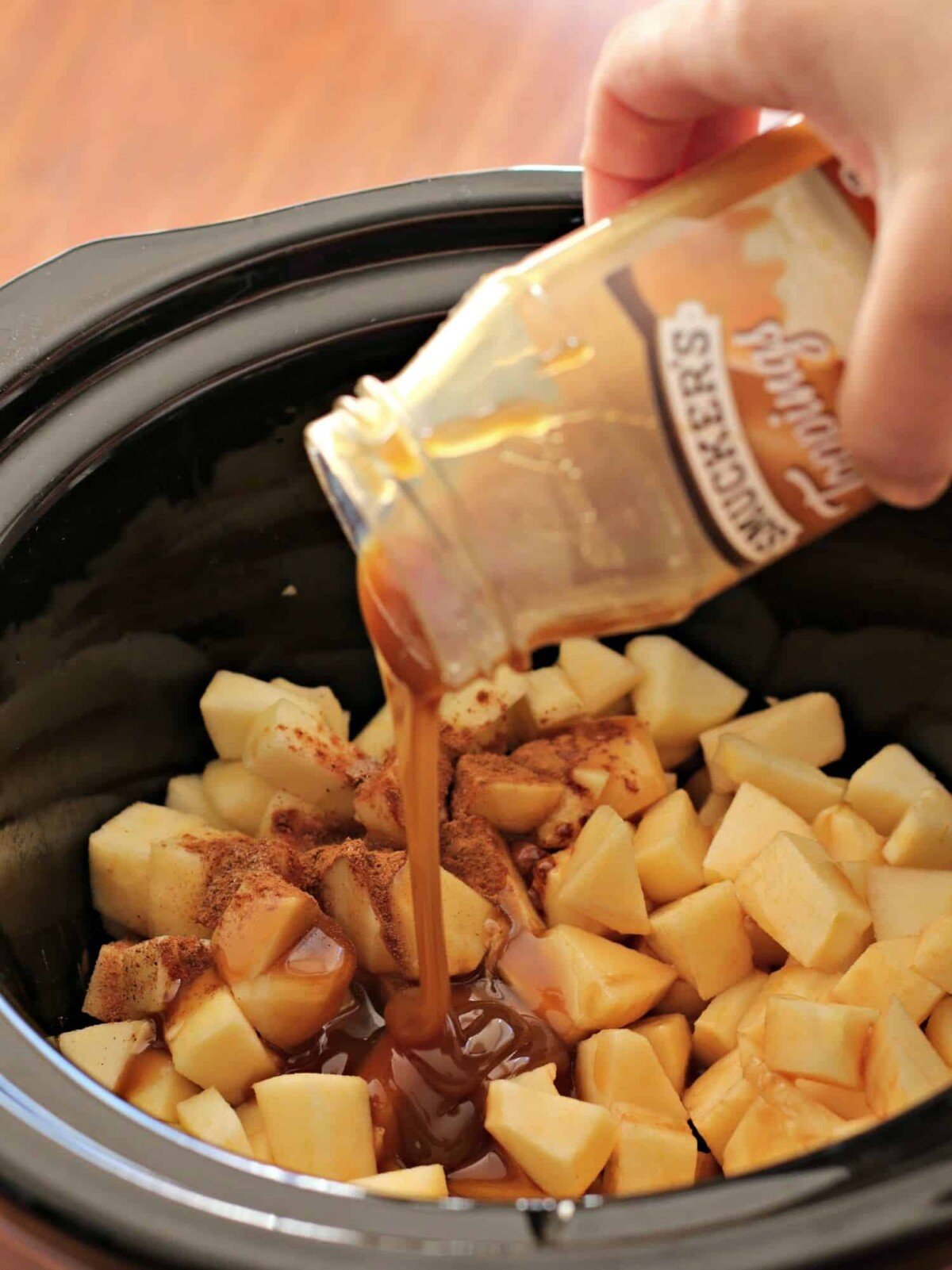 caramel being poured over apples.