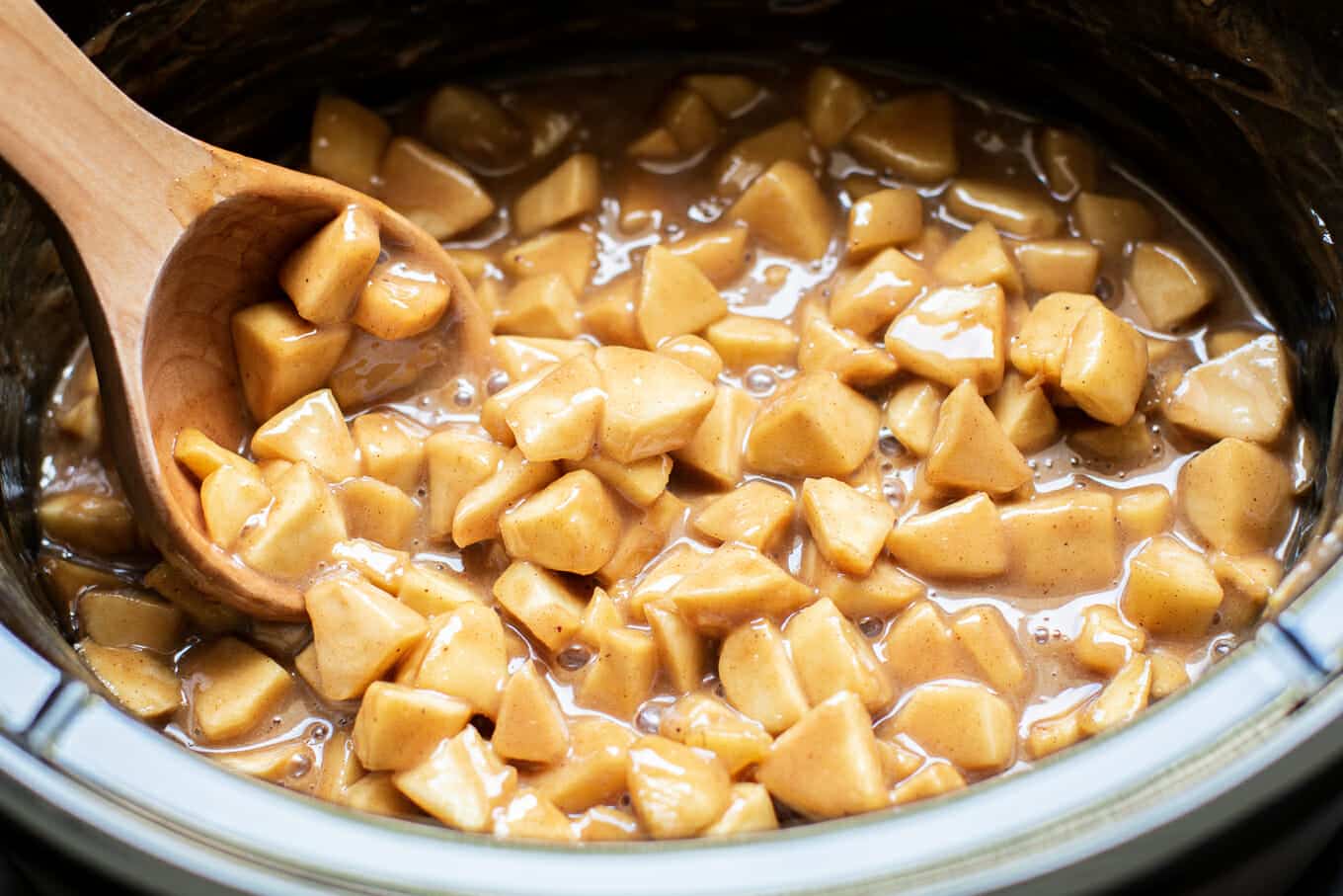 Caramel apple pie dip with wooden spoon in it.