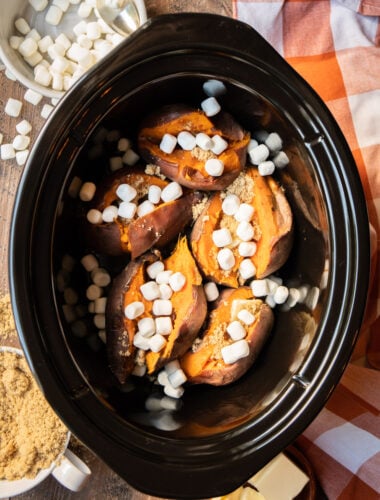 5 cooked sweet potatoes in the slow cooker with marshmallows and brown sugar on top.
