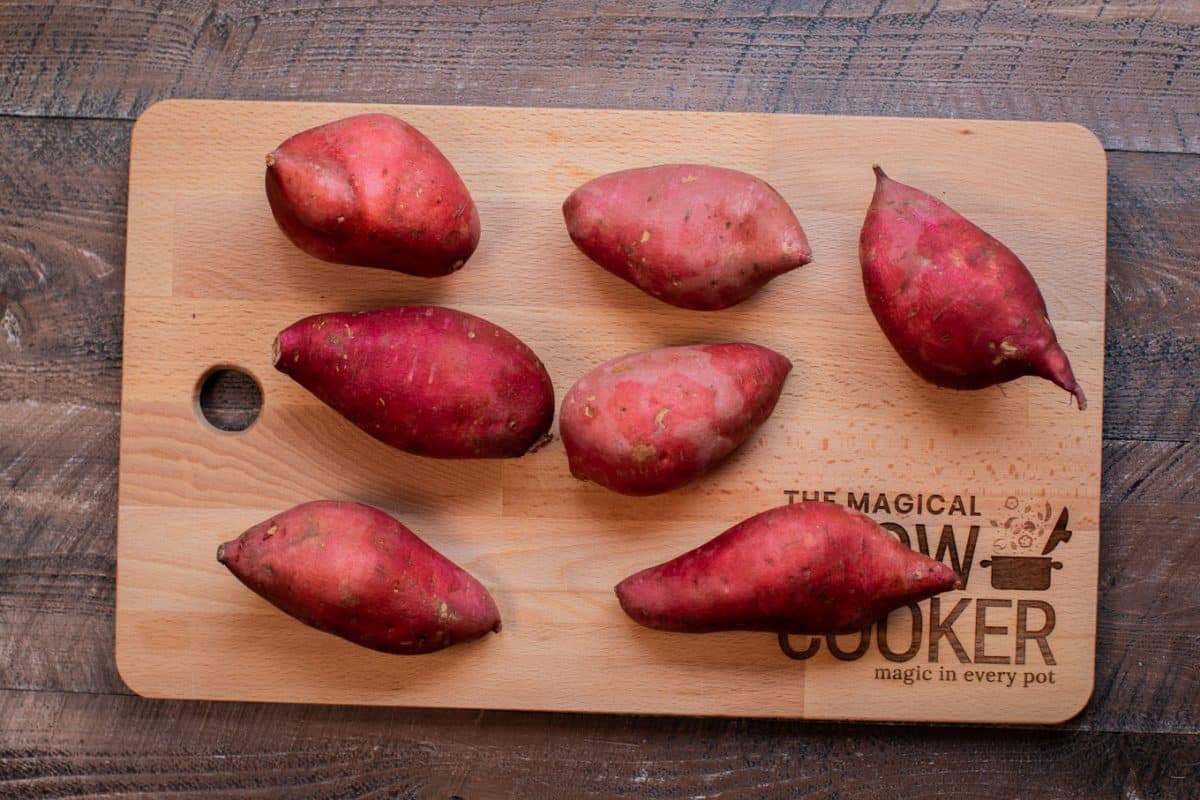 8 uncooked sweet potatoes on a cutting board