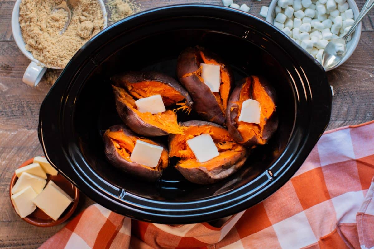 5 sweet potatoes in the slow cooker with pats of butter on top.
