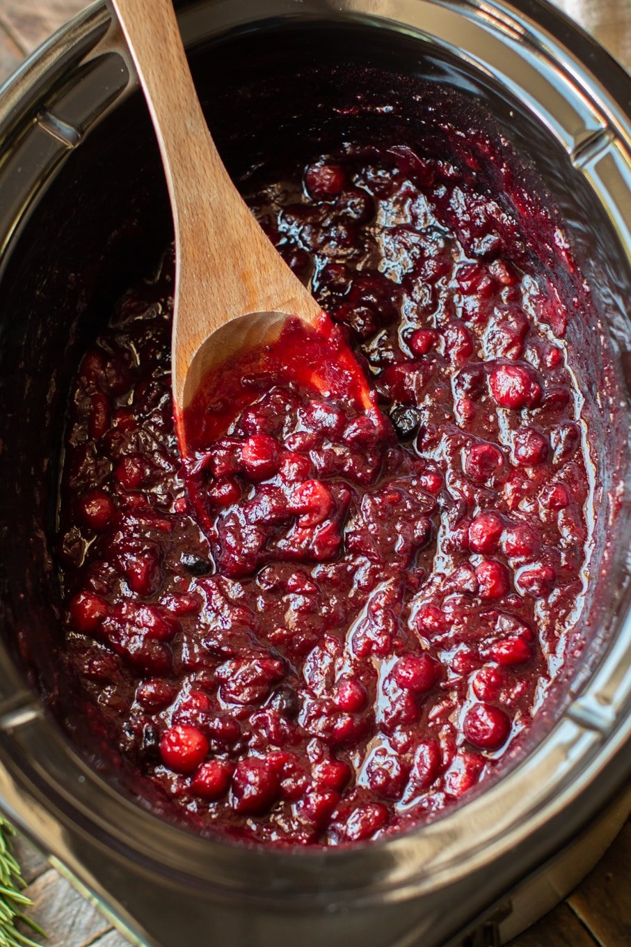 close up of bright burgundy colored cranberry sauce in a slow cooker.