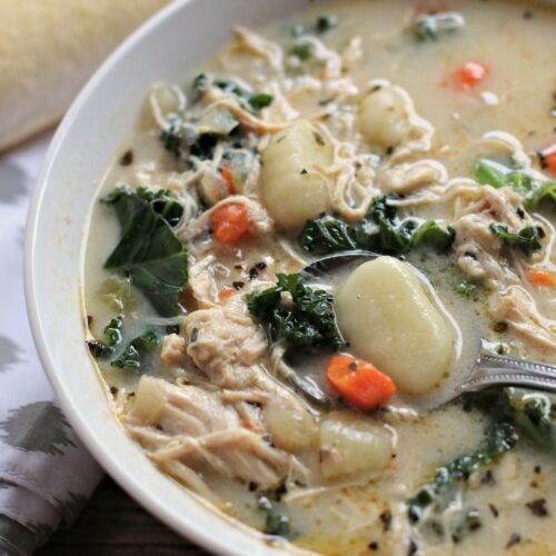 chicken, gnocchi and kale soup in white bowl with spoon in it.