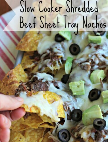 Nachos on sheet try with hand grabbing a chip.