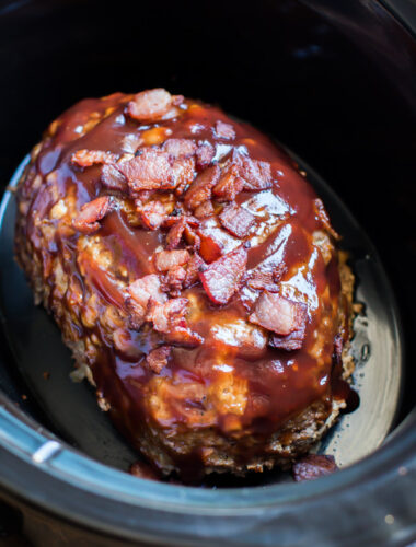 Meatloaf in the slow cooker with barbecue sauce and cooked bacon top.