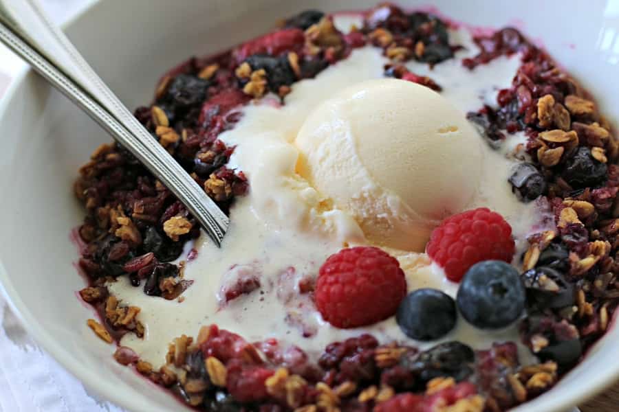 bowl of berry crisp with ice cream on top.