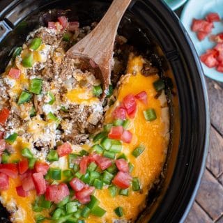 Slow cooked casserole with ground beef, sour cream, melted cheese, tomato and bell pepper on top.