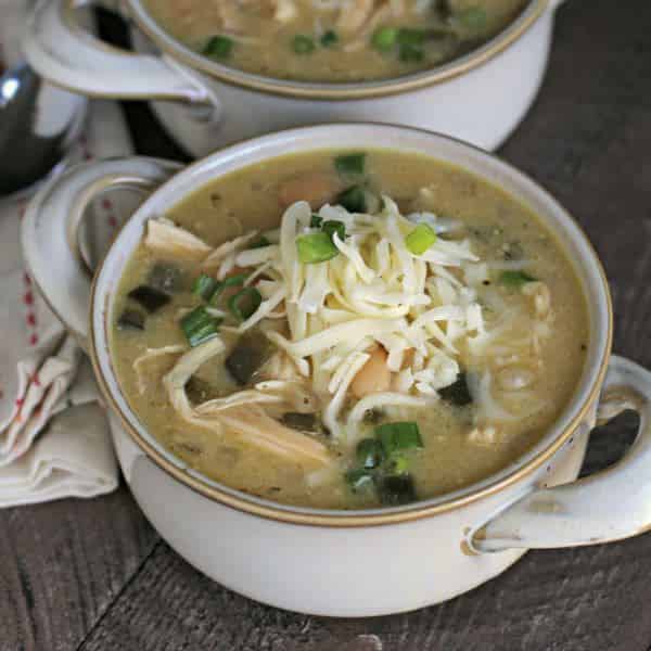 soup crock of white chicken chili with cheese and green onions on top