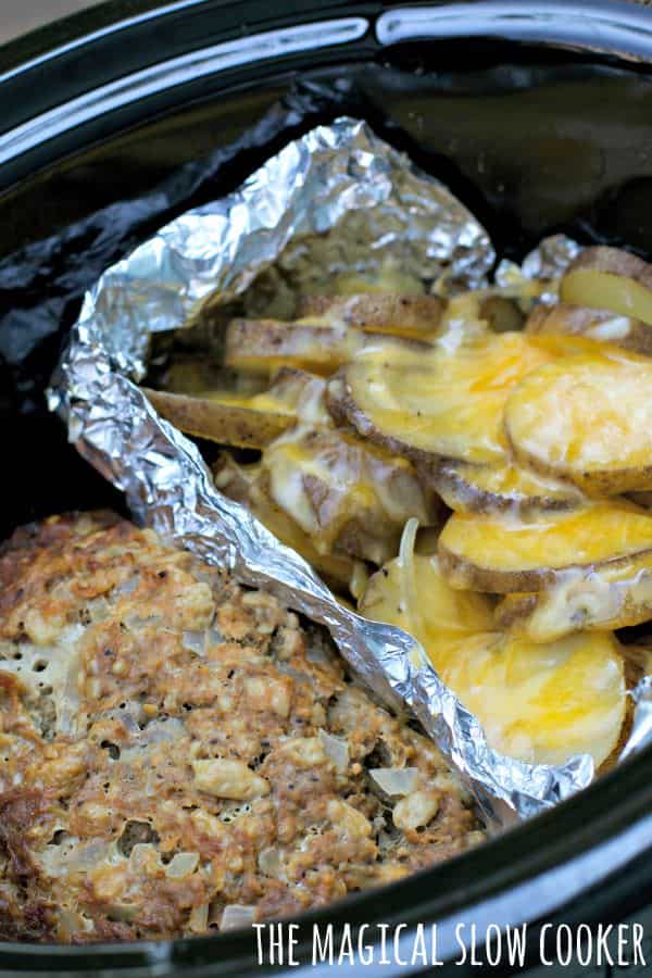 small meatloaf and cheesy potatoes in foil, in slow cooker