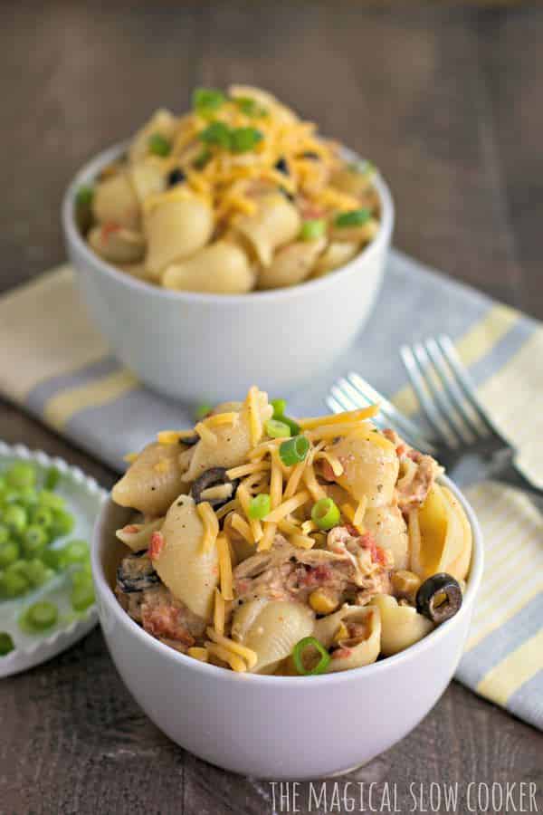 bowl of shell pasta with cheese and green onion on top.