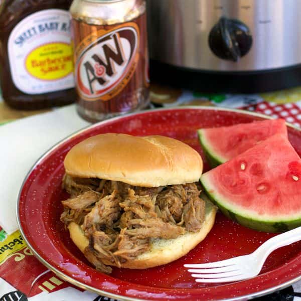 root beer pork on a bun with watermelon on the side.