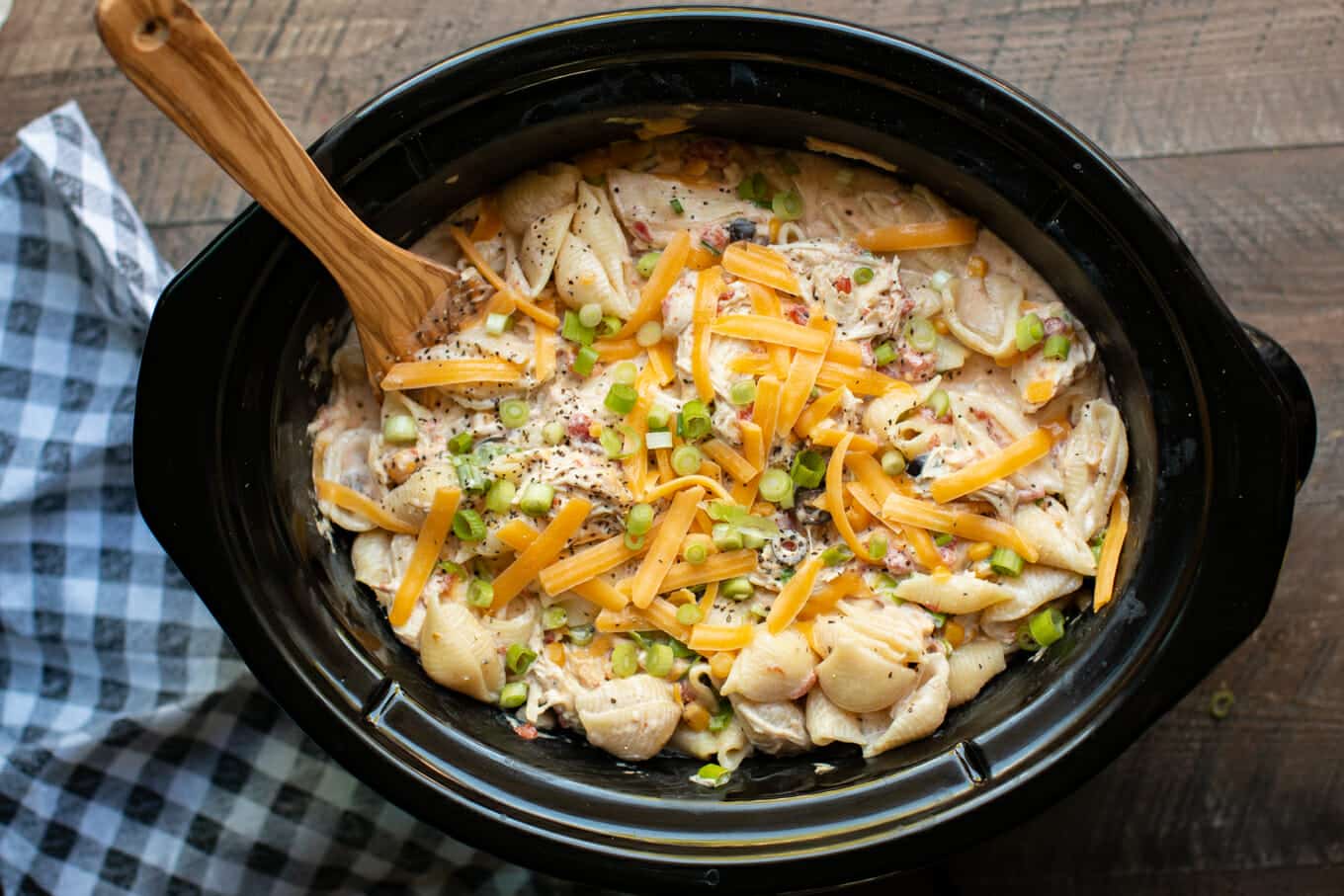 serving shell pasta dish with chicken, cheese and green onion on top from a slow cooker.
