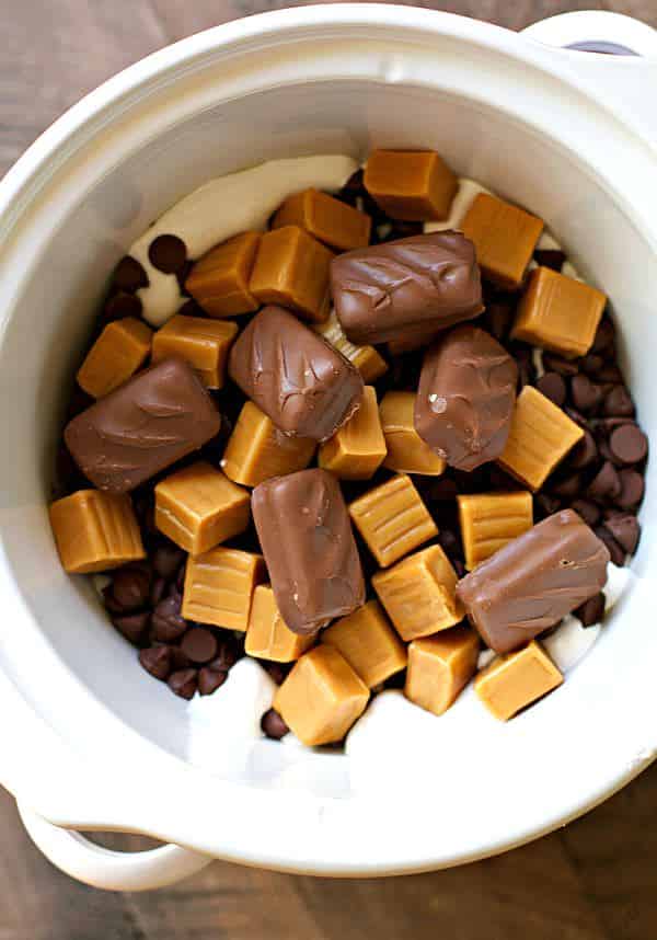 candy bars, caramels, chocolate chips, and marshmallow fluff in slow cooker.