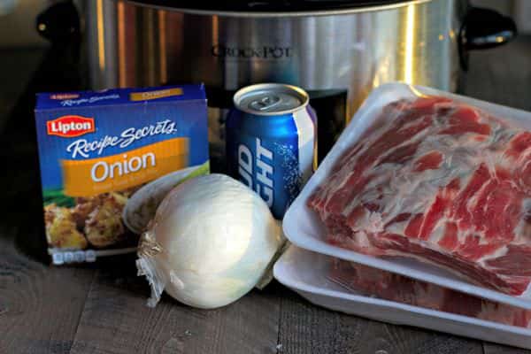 beef ribs, onion soup mix, can of beer and onion in front of slow cooker