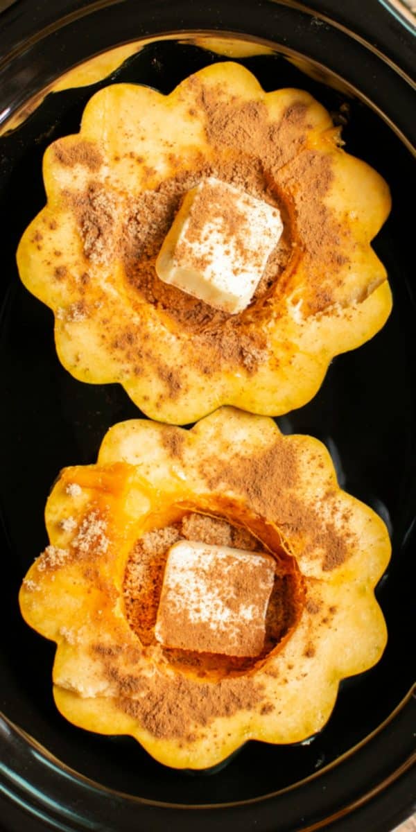 close up of acorn squash in slow cooker with butter and spices on top.