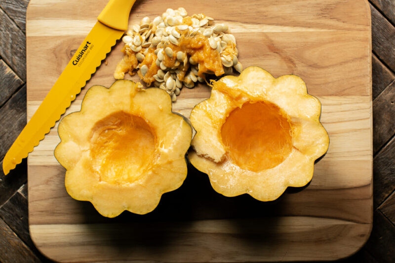 cut open acorn squash with seeds gutted out on cutting board