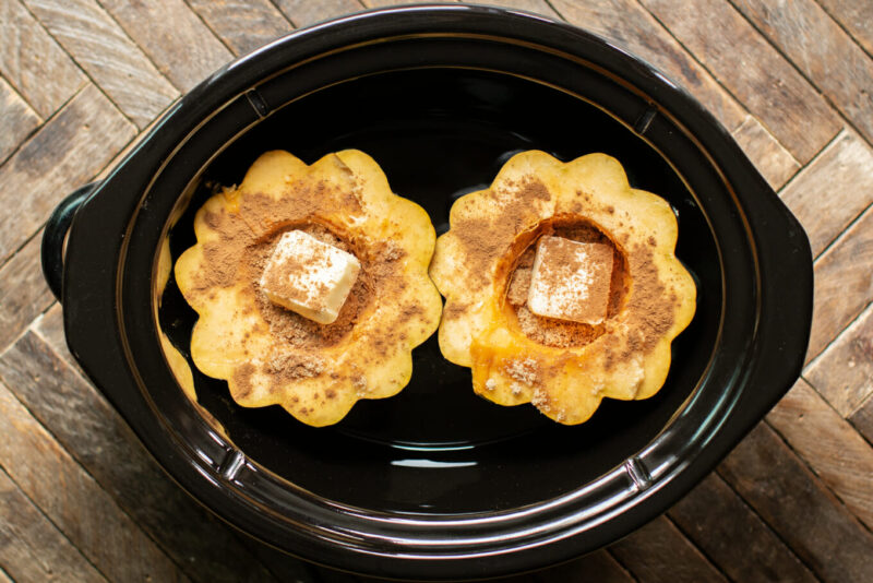 cut acorn squash with butter and spices on top.