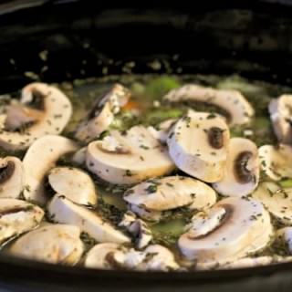 Uncooked soup with mushrooms floating on top.