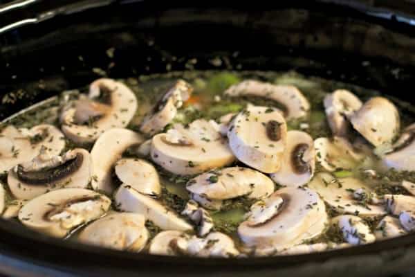 uncooked turkey soup in the slow cooker. Mushrooms floating on top.