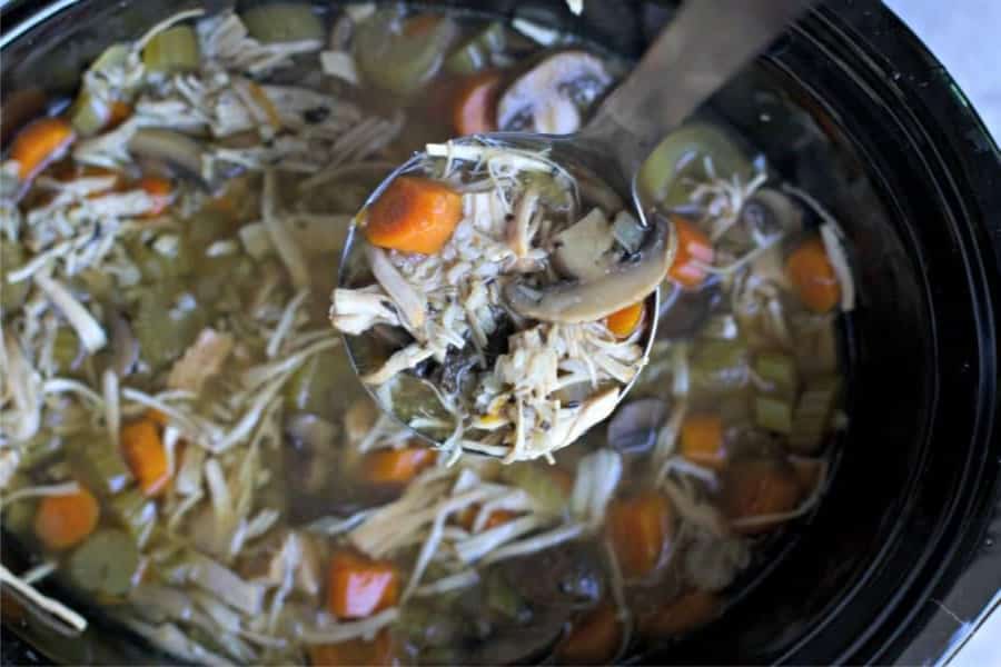 ladle of turkey and rice soup scooping from slow cooker.