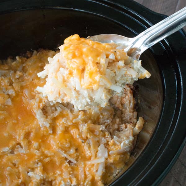 Close up of cheesy hashrbrowns on metal spoon.